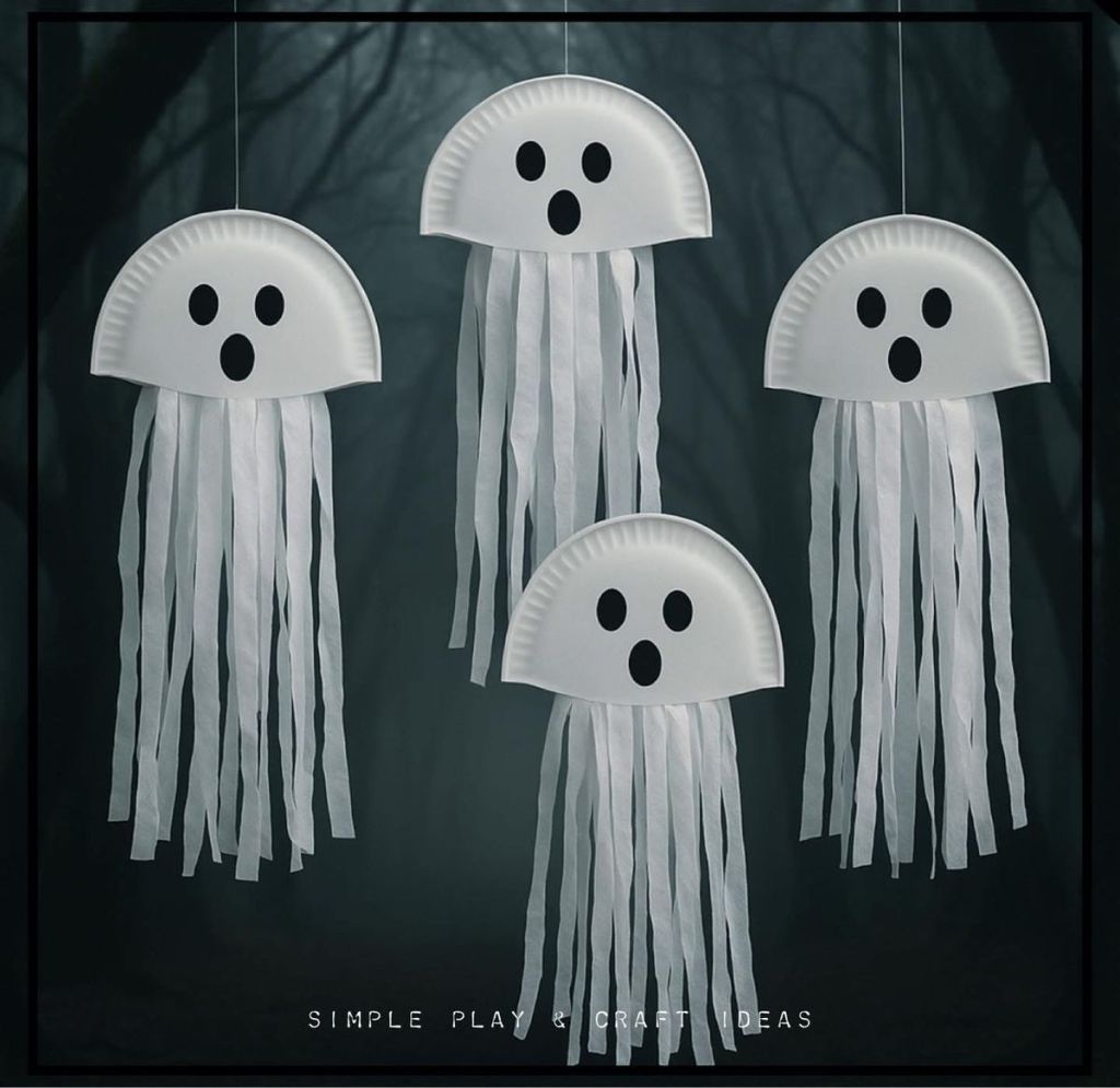 Cuatro fantasmas colgantes hechos de platos de papel con tiras blancas como tentáculos, sobre un fondo oscuro.